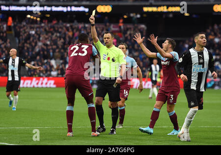 Referee Stuart Attwell gives West Ham United's Issa Diop (left) a yellow card during the Premiership match at The London Stadium, London. Stock Photo