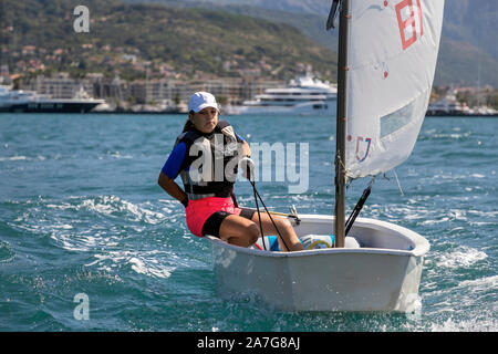 Montenegro, Sep 20, 2019: Teenage girl sailing in Optimist Class dinghy during the regatta in Kotor Bay Stock Photo