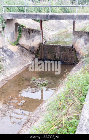 Concrete weir of the small canal in the irrigation system for distribution the water to the plantation area in the countryside of Thailand. Stock Photo