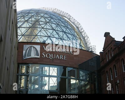 One of the entrances to Belfast's Victoria Square shopping centre with the glass geodesic dome rising between the traditional city centre buildings. Stock Photo