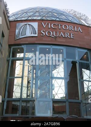 One of the entrances to Belfast's Victoria Square shopping centre with the glass geodesic dome rising between the traditional city centre buildings. Stock Photo