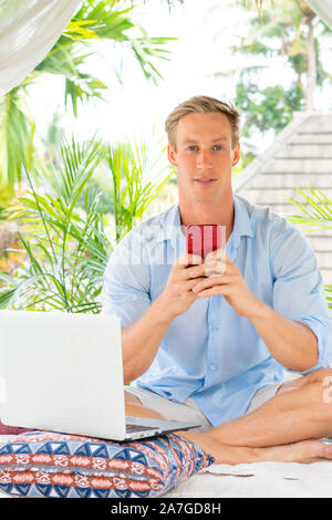 Attractive man using smartphone with palms on the background Stock Photo