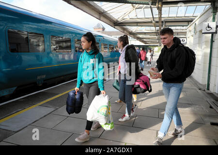 Young people women students with rucksacks and bags getting on KeolisAmey run train at Bangor railway station in Gwynedd North Wales UK  KATHY DEWITT Stock Photo