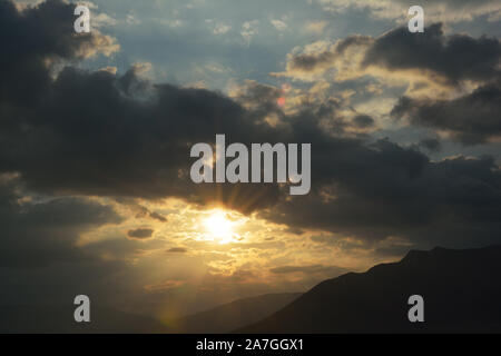 Sun shining through clouds over the mountain Stock Photo