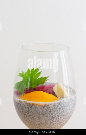 Glass of chia healthy food coconut pudding with banana, mango and dragon fruit on the white background. Healthy concept. Stock Photo