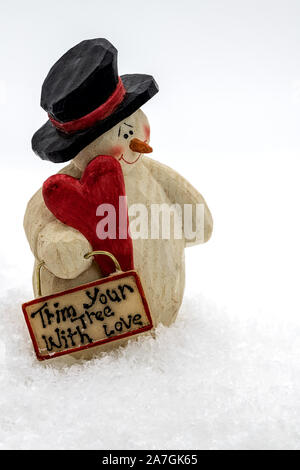 funny snowman standing in the snow holding a heart and a sign in its hand Stock Photo