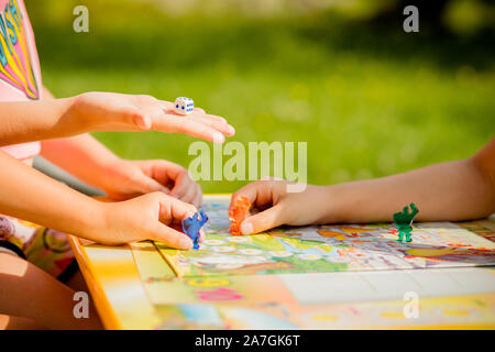 Family playing a board game at home, one kid is on the move and capturing the piece of another player Stock Photo