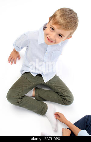 Handsome little boy getting tickled to his feet by his friend and smiling Stock Photo
