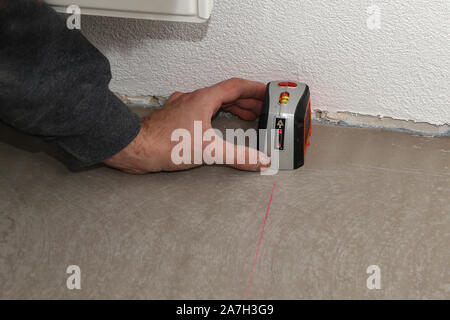 Man using cross-line laser to mark the floor Stock Photo