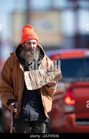 Homeless man panhandles for money at a busy intersection near a homeless encampment under a highway overpass days before a threatened crackdown by Texas Governor Greg Abbott on public right-of-way camping. Stock Photo