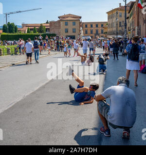 Pisa, Italy - August 28, 2018: Tourists posing before Pisa leaning tower for creative photos Stock Photo