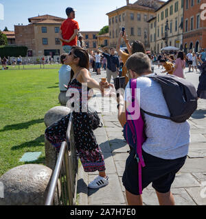 Pisa, Italy - August 28, 2018: Tourists posing before Pisa leaning tower for creative photos Stock Photo