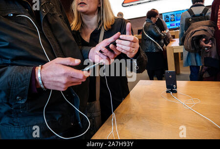 Paris, France - Nov 3, 2017: Side view of young couple admiring inside Apple Store the latest professional iPhone smartphone manufactured by Apple Com Stock Photo