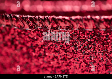 Macro background of brightly lit beautiful sparkling red glitter fabric ribbon texture with bokeh Stock Photo