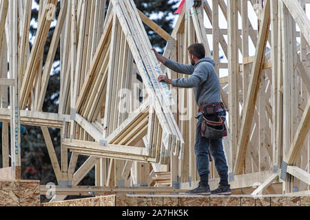 Housing construction workers installing roof trusses on a new home Stock Photo