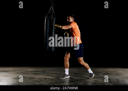 Boxer man during boxing hitting heavy bag at training fitness gym Stock Photo