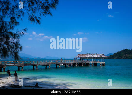 Beautiful jetty in the backdrop of clear blue waters and mountain. Stock Photo