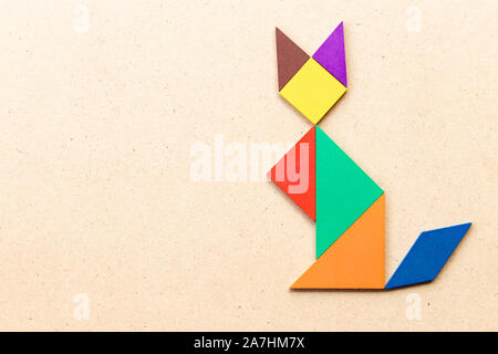 Color tangram puzzle in sitting cat shape on wood background Stock Photo