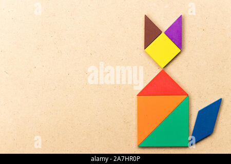 Color tangram puzzle in sitting cat shape on wood background Stock Photo