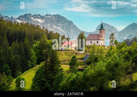 Slovenian mountain landscape with church. St Spirit ( Sveti Duh) church on the mountain ridge and Kamnik-Savinja Alps in background, Slovenia, Europe Stock Photo