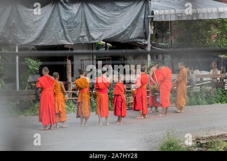 Monks in orange robes collect food donations in the morning. Monks on the streets in the city of Pakse, Laos. Stock Photo