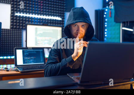 Hacker in hood shows thumbs up, network criminal Stock Photo