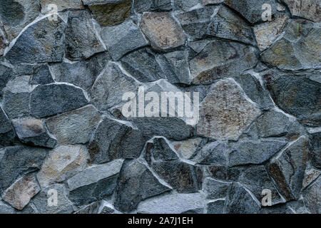 Gray stone wall background. Abstract rock texture. Modern style. Facade, building details. Mosaic of bricks. Grey grunge surface. Natural pattern. Stock Photo