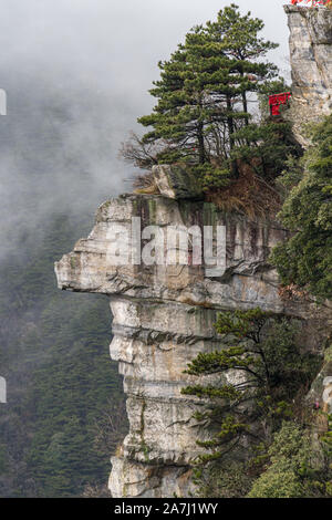 Rock / mountain shaped like a face with trees on top on a foggy day Stock Photo