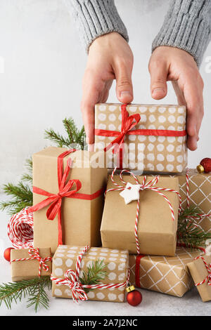 Male hands taking a beautifully decorated gift box from a big stack of gifts. Xmas preparation. Stock Photo