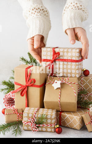 Young woman hands taking a beautifully decorated gift box from a big stack of gifts. Xmas mood. Stock Photo