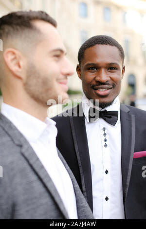 Focus on afroamerican man standing near caucasian boy wearing suit. Stock Photo
