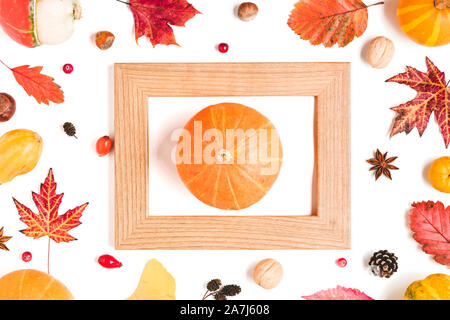 Thanksgiving or autumn background. Fall frame made of fallen leaves, dry flowers, berries, nuts and pumpkin in frame isolated on white background. Cre Stock Photo