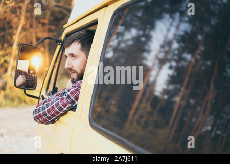 Young Caucasian man looking out of the window of his campervan Stock Photo