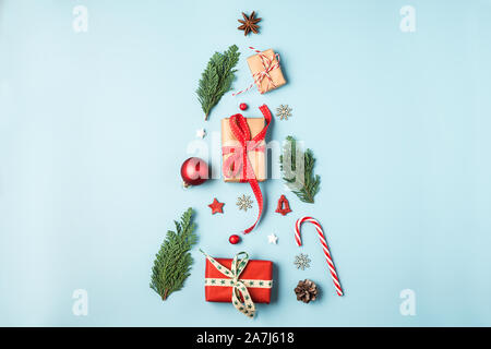 christmas tree made from fir branches, winter decorations, candy and gift boxes on blue background. holiday creative concept. new year or christmas ba Stock Photo