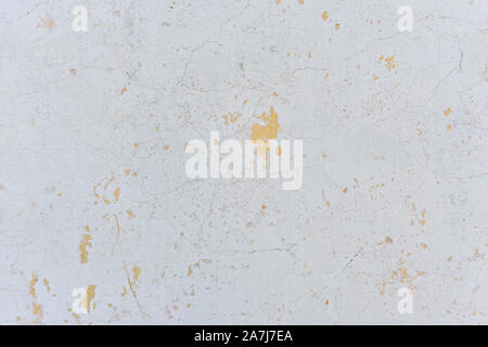 White wall in cracks with the remnants of plaster and old paint. Background. Stock Photo