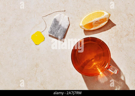 Cup of tea, lemon and teabag on marble table with harsh summer sunlight. Overhead view with copy space Stock Photo