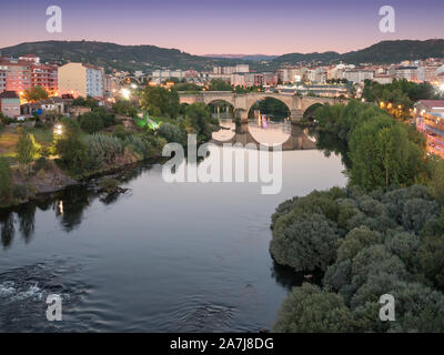Time-blended image of the Roman bridge over the Miño River at sunset, as seen from the Millenium bridge, in Ourense, Galicia, Spain Stock Photo