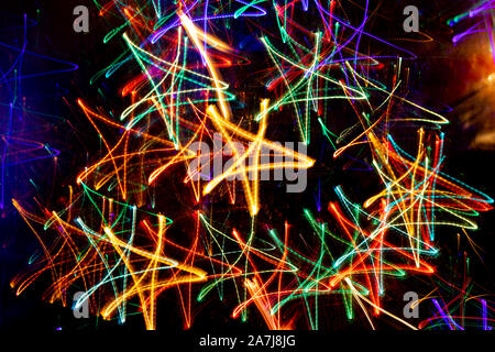 Lot of multicolored neon glowing stars on black background. Abstract trendy neon christmas background. Photographic effect of long exposure while movi Stock Photo