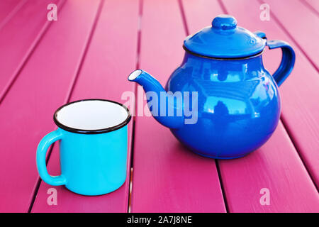 Blue vintage ceramic teapot and teacup on pink wooden table background under natural morning light. Morning tea. Stock Photo