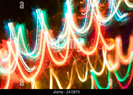 Close-up blurred glowing diagonal neon waves on dark.  Abstract neon luminous background. Photographic effect of long exposure while motion. Stock Photo