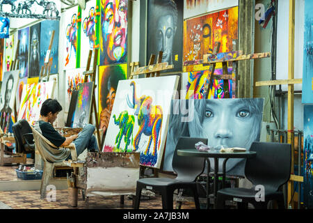 Khao Lak, Thailand, August 30, 2019: street artist paints and sells in the evening Colorful paintings from unknown local artists in store at tradition Stock Photo