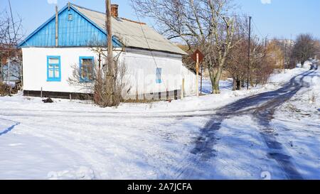 Winter rural landscape with a small house and a country road. Difficult weather conditions with ice and sleet Stock Photo