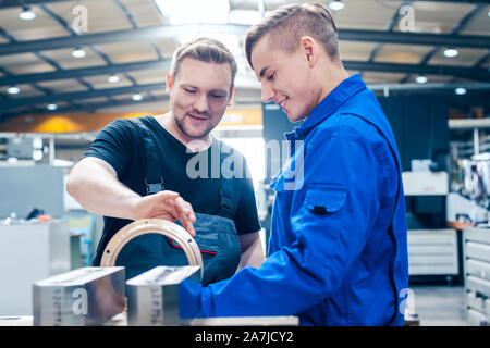 Master discussing a workpiece with his apprentice or trainee Stock Photo