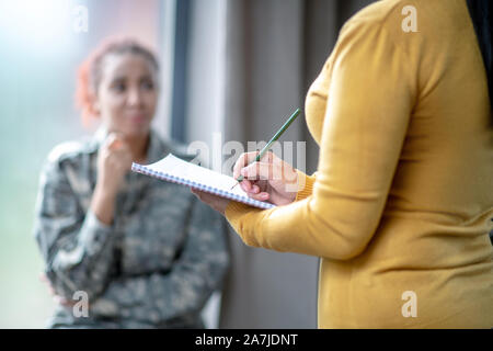 Female psychoanalyst wearing yellow sweater making notes Stock Photo