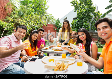 Group-of Three-Generation Family membersÂ  Eating Healthy Breakfast in-Morning At-courtyard of their house Stock Photo