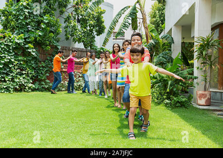 Large group of happy families Members walking Together in-train formation in front of their house in the garden Stock Photo