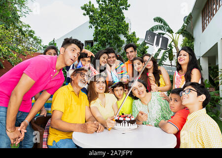 Large group-of Indian family members taking Selfie Photo With Monopod During Birthday Celebration in-courtyard of their house Stock Photo