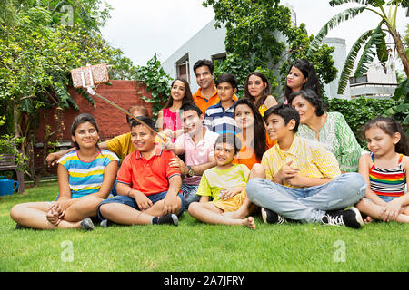 Large group-of Indian-family membersÂ taking Selfie Photo with smartphone on selfie stick in-Courtyard near their houseÂ Stock Photo