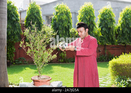 Indian Hindu Traditional male water pouring in holy Tulsi Plant Puja in-courtyard of-their house Stock Photo