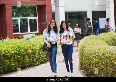 Full-Length of Two College Girls Student Friends Together Reading Book Studying Education In-Outside Campus Stock Photo
